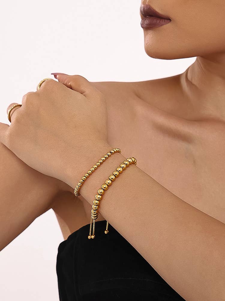 Dainty gold beaded bracelet stacked on wrist with other bracelets
