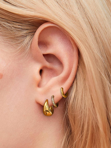 Woman wearing stacked gold hoop earrings in three sizes, 18K gold plated boutique jewelry