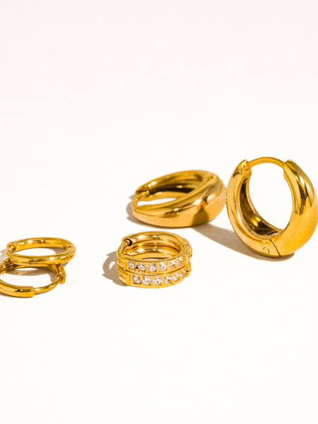 Gold hoop earrings and rings on a white background