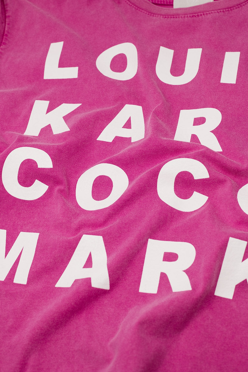 Close-up of designer names graphic print on fuchsia cotton tee