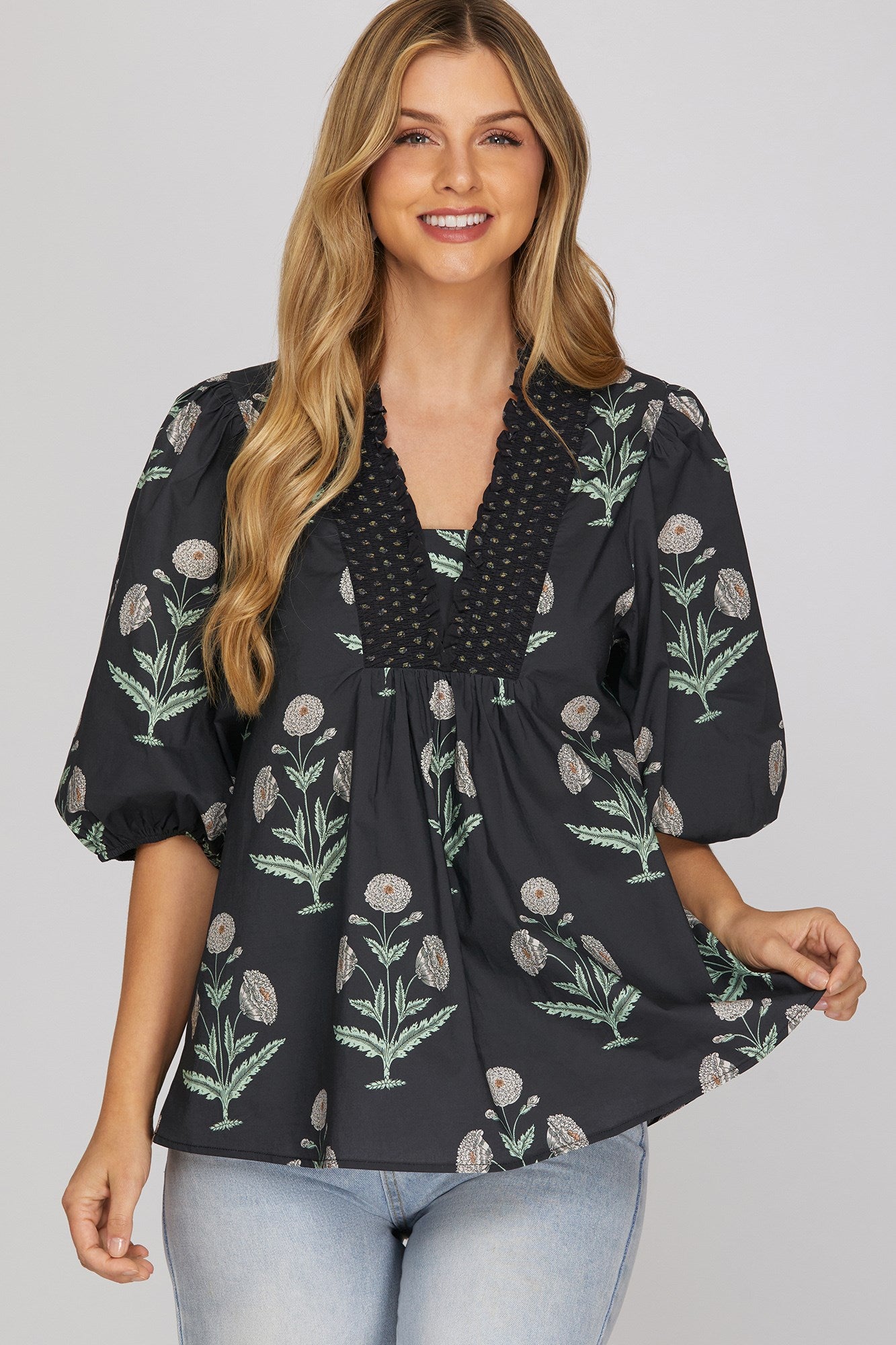 Woman wearing navy botanical floral print smocked V-neck top with puff sleeves and jeans
