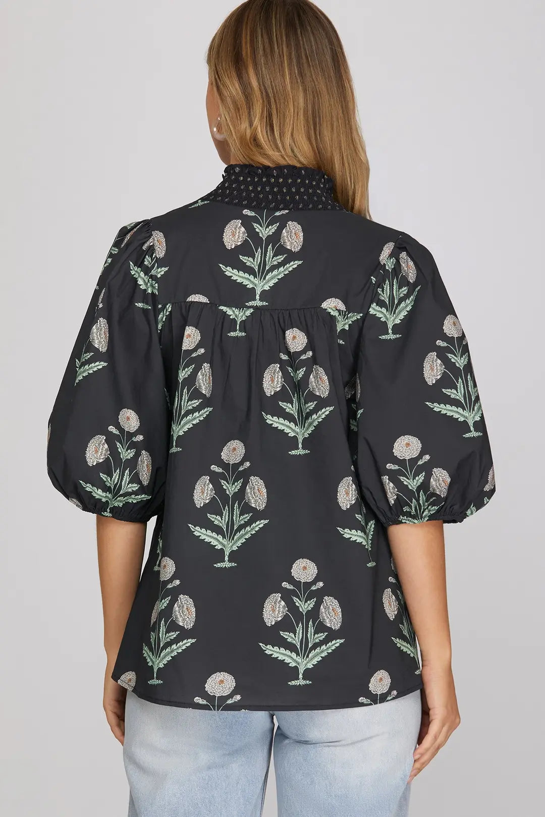 Woman wearing navy botanical floral print smocked V-neck top with puff sleeves and jeans
