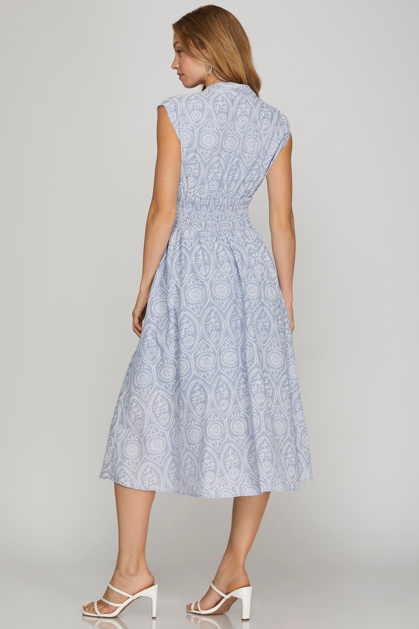 Woman wearing a light blue patterned dress on a plain background