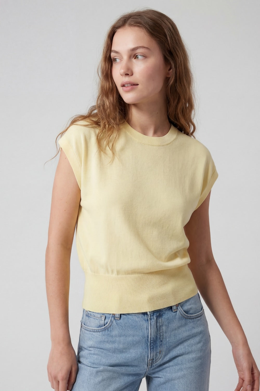 Yellow fine knit sleeveless top with wide ribbed waistband, front view on model
